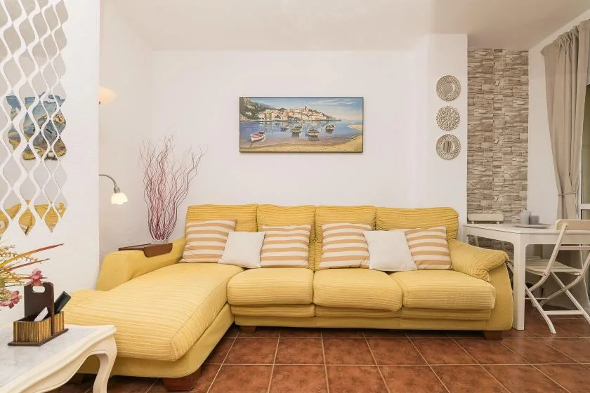 A living room with yellow seating arranged around a framed painting.