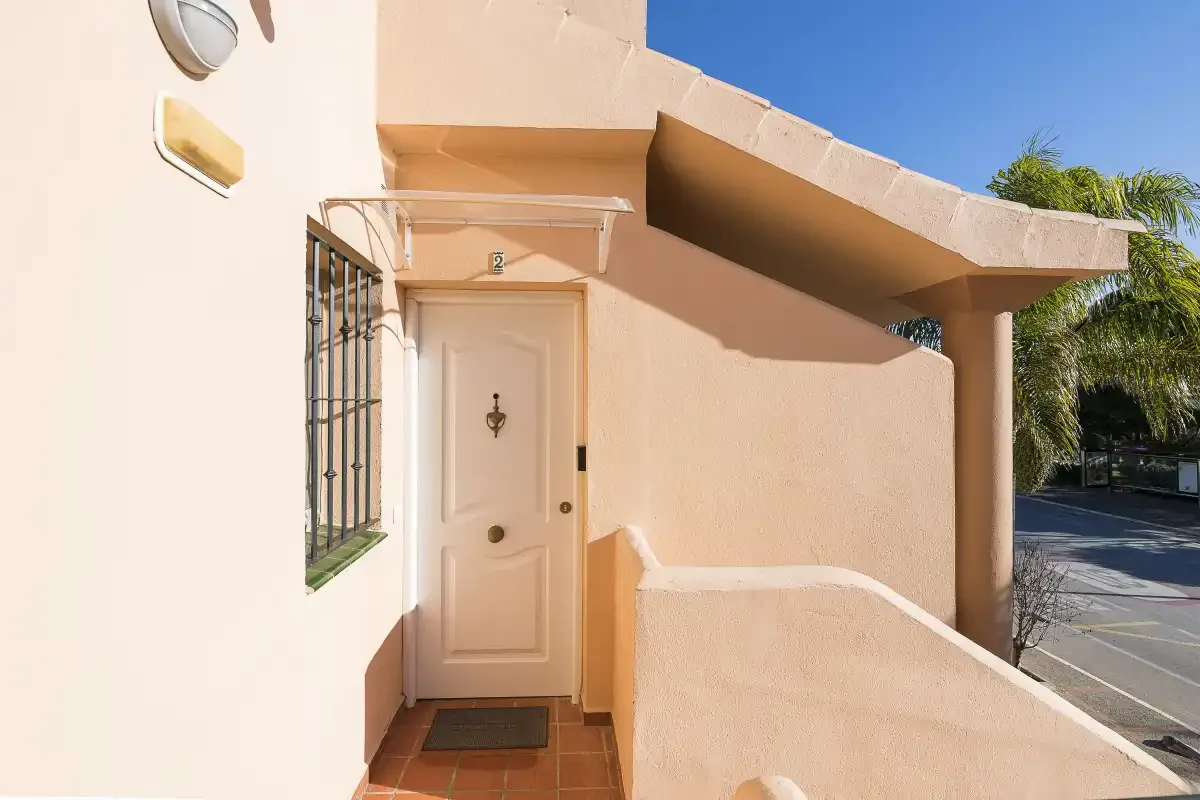 An exterior entryway with a white door, tiled steps, and a covered walkway.