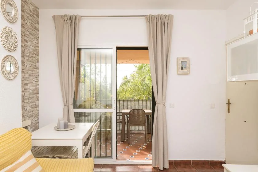 A bright living room opens onto a small terrace through sliding glass doors.