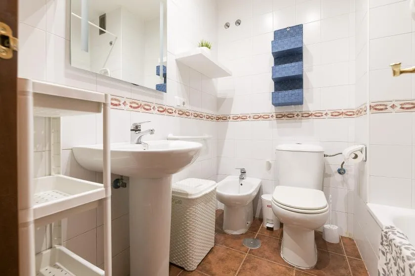 A tiled bathroom with a sink, toilet, bidet, and bathtub.