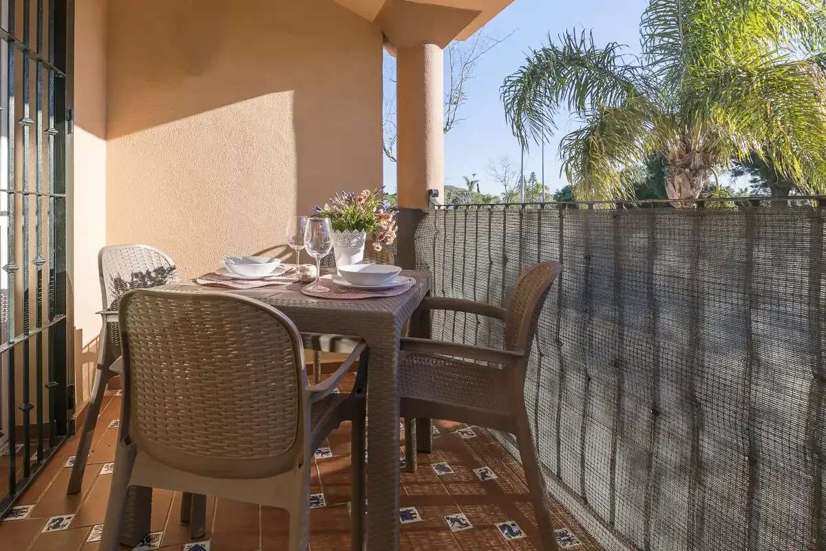A tiled outdoor dining area with a table, chairs, and a screened railing.