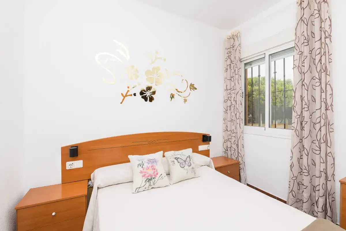 A bright bedroom with a double bed and a window beside it.
