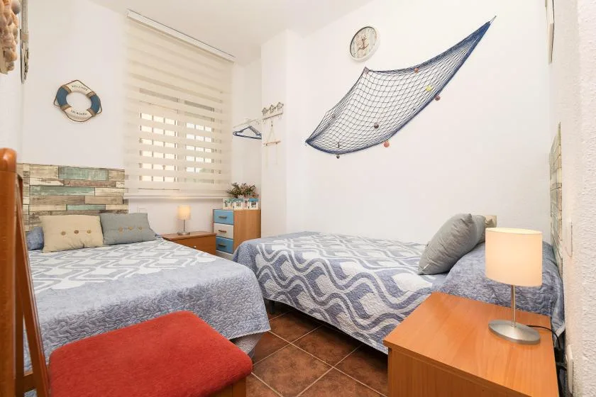 A bedroom with two beds, patterned bedding, and a bedside lamp.
