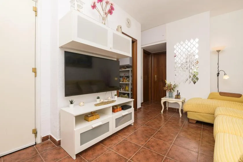 A living room with a television above a white media console and yellow seating.