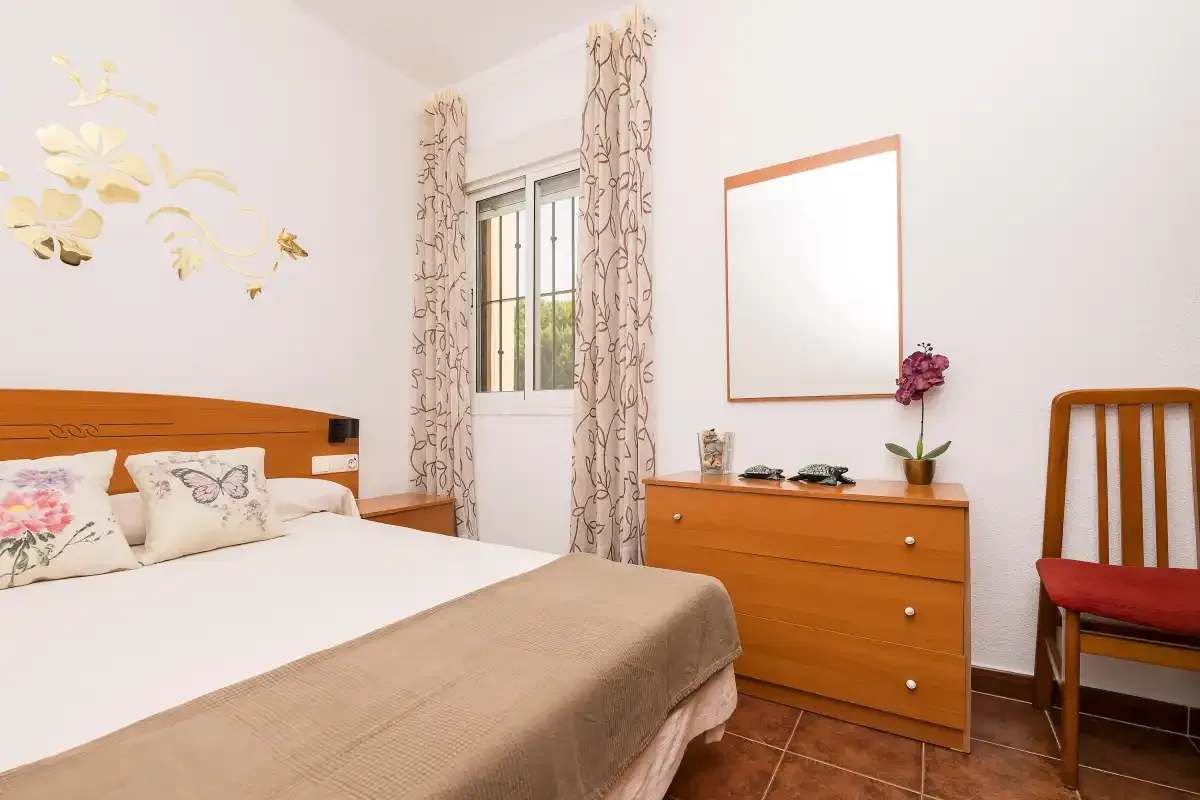 A bedroom with a bed, dresser, and window.