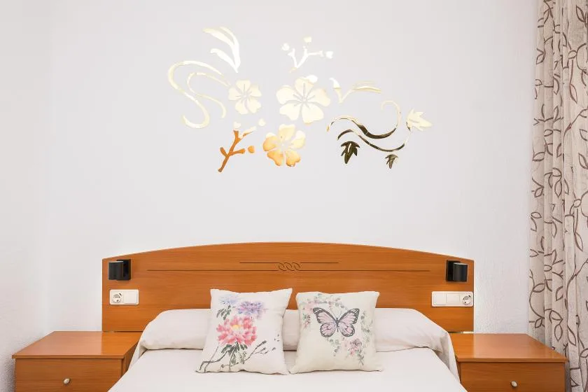 A bedroom with a bed beneath floral wall decorations and patterned curtains.