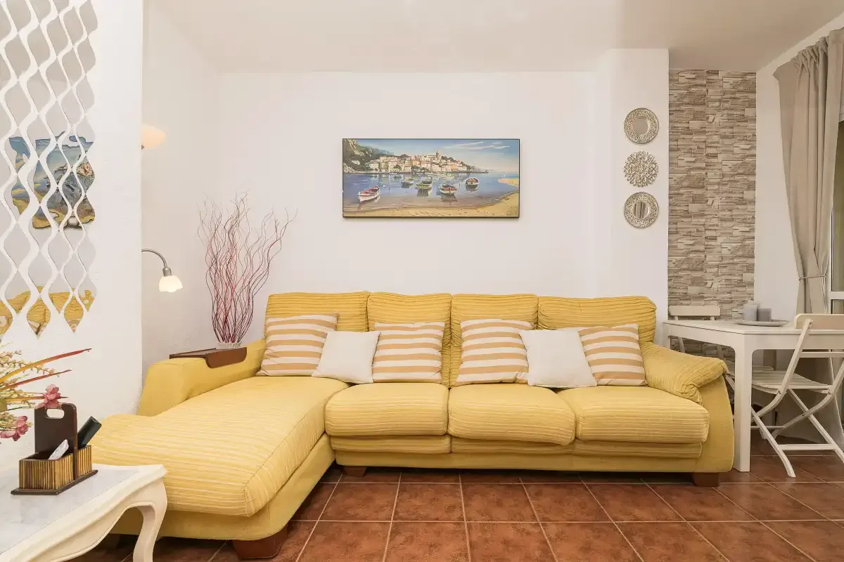 A living room with yellow seating and a framed painting on the wall.