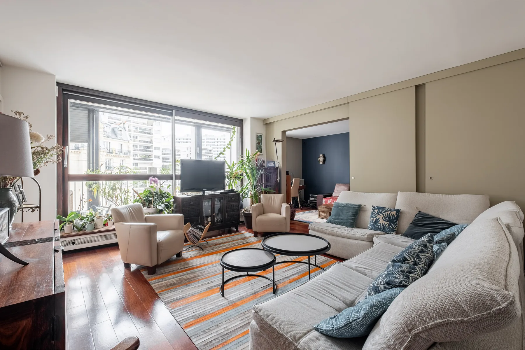 Living room with seating around coffee tables and large windows.