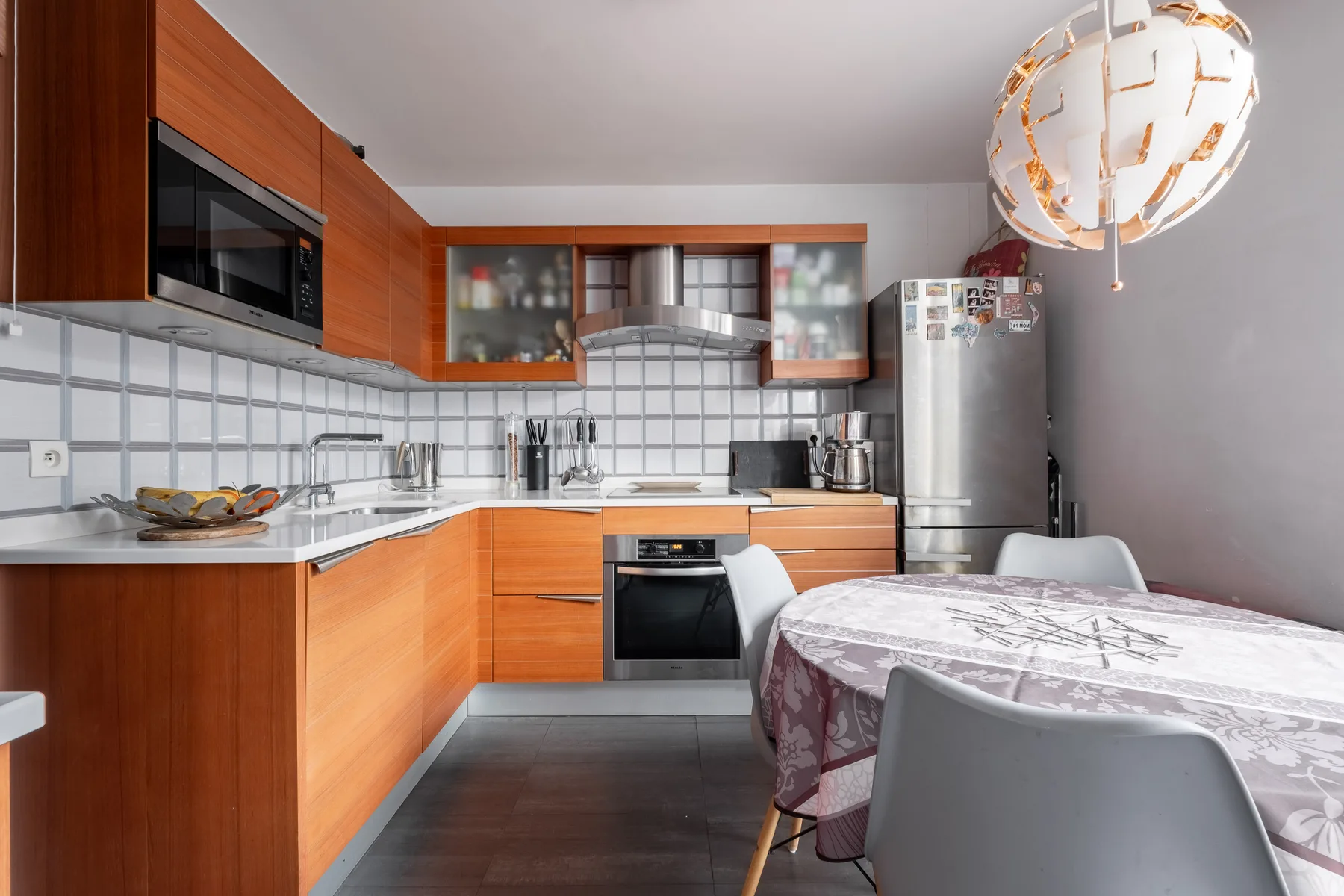 A modern kitchen with wood cabinets and a dining table in the foreground.