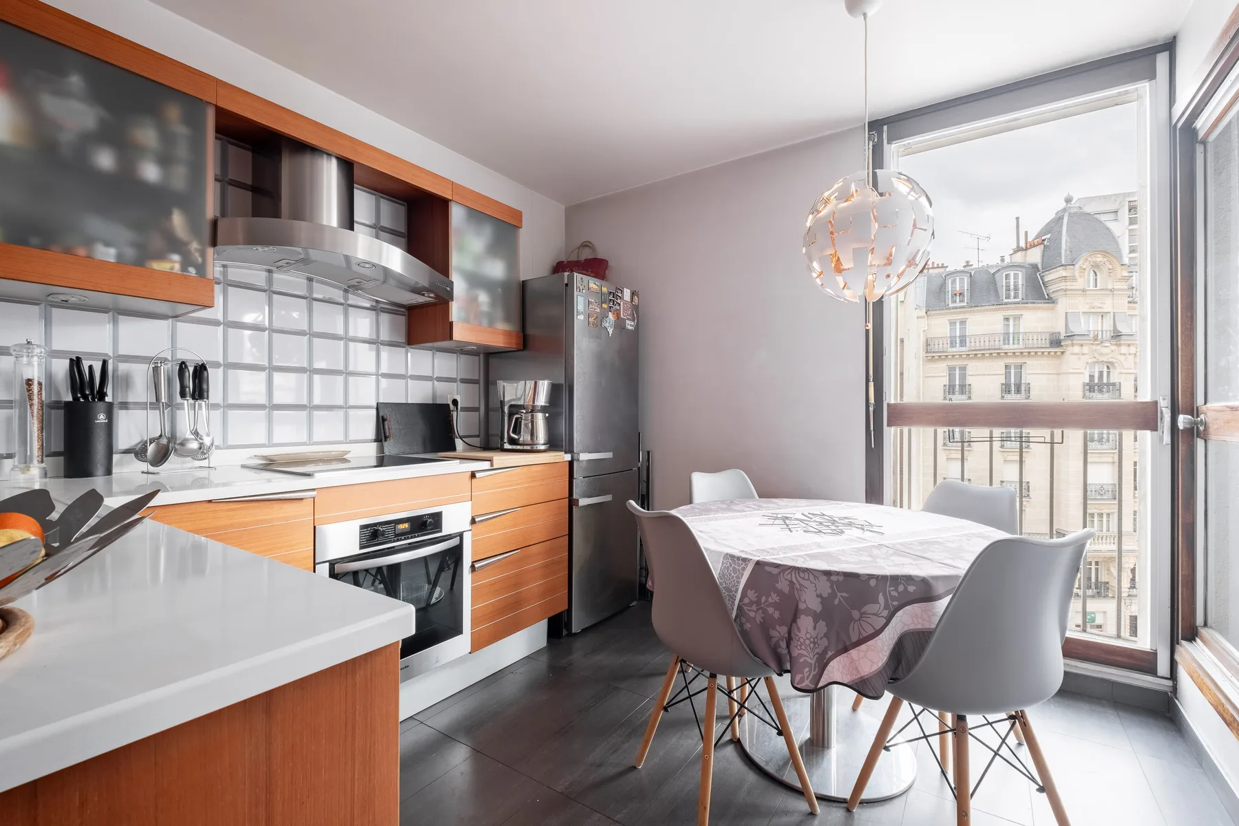 A modern kitchen and dining area with a table beside large windows.
