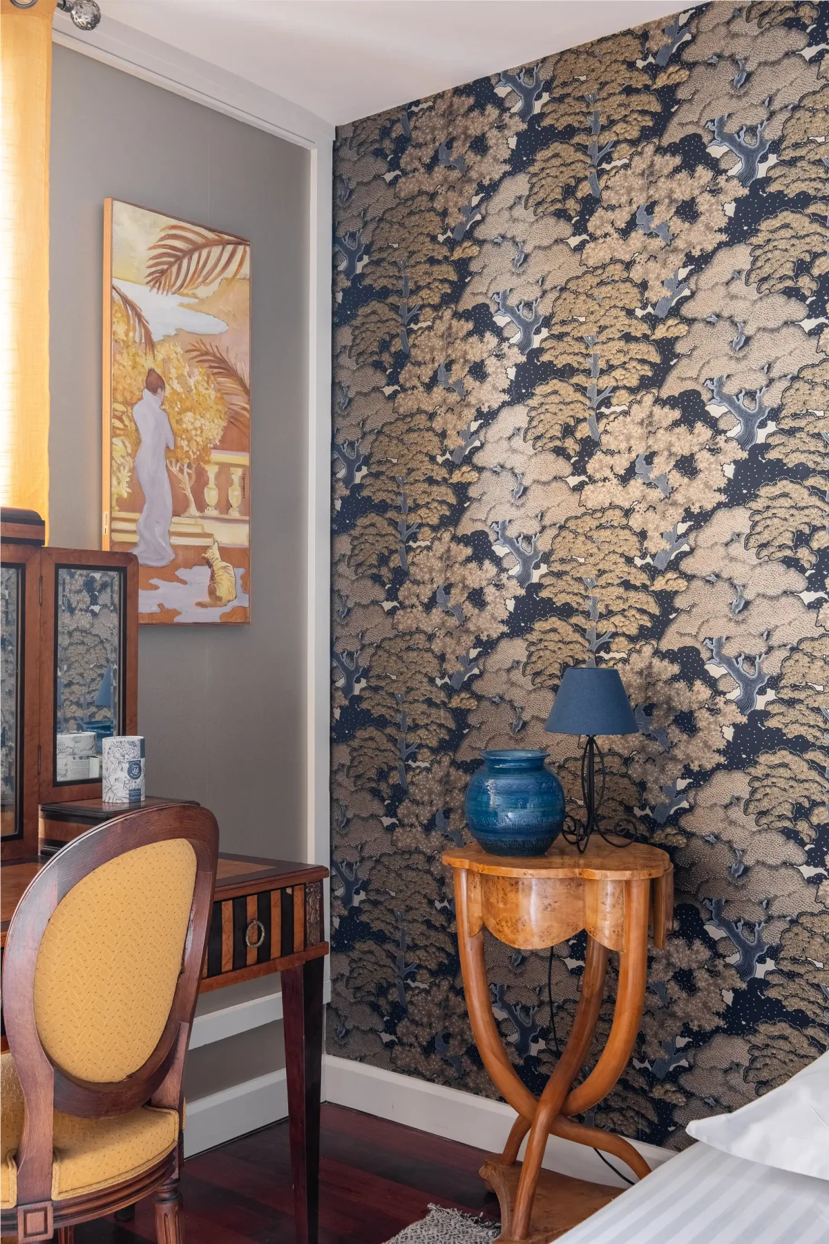 A bedroom corner with patterned wallpaper, a small table, and seating.