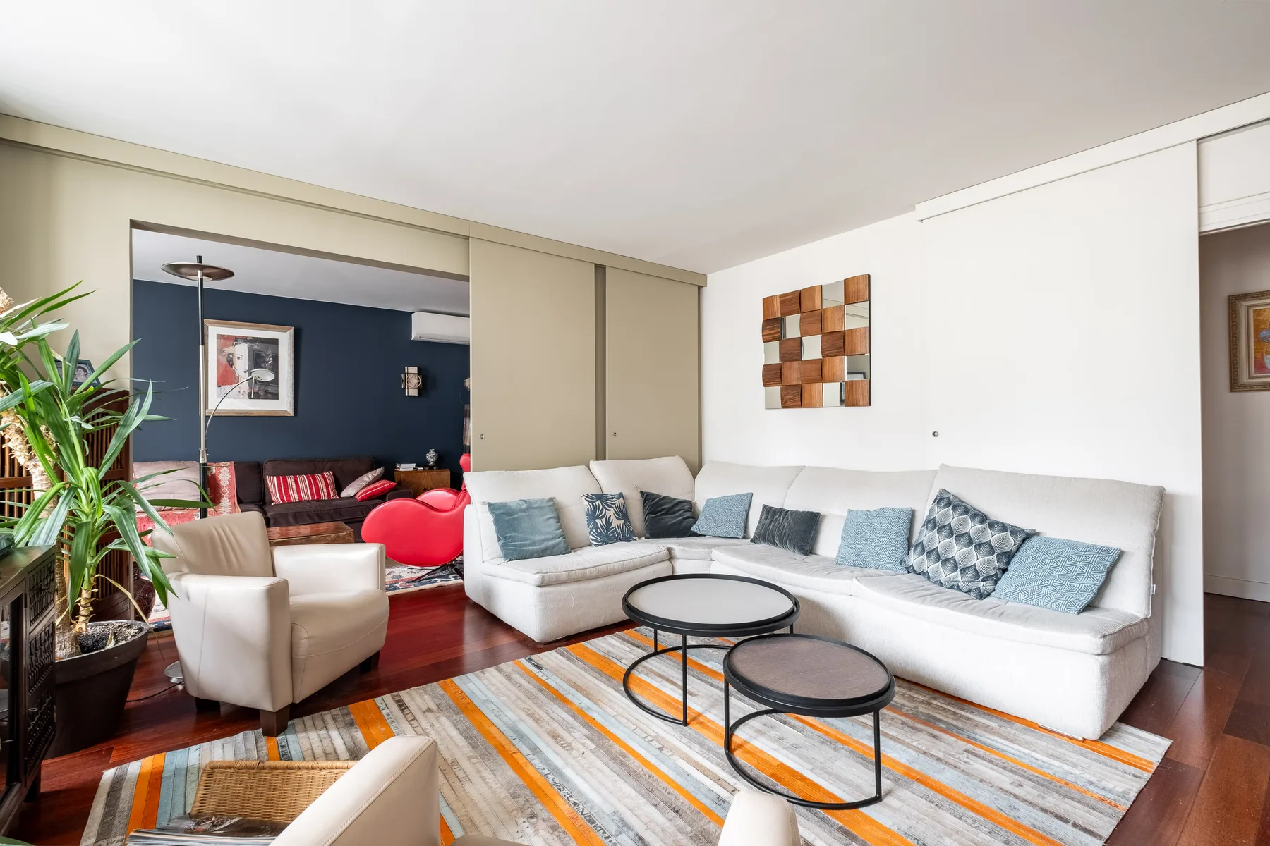 A bright living room with a white sectional, colorful rug, and round coffee tables.