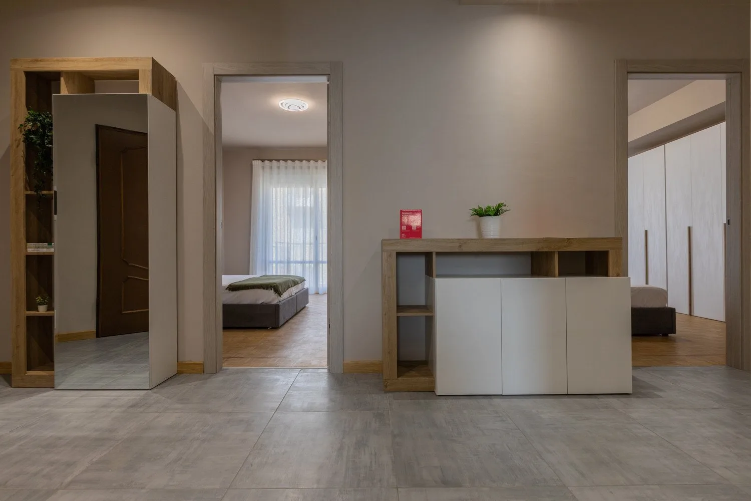 A furnished bedroom is visible through open doorways, with a low cabinet in the foreground.