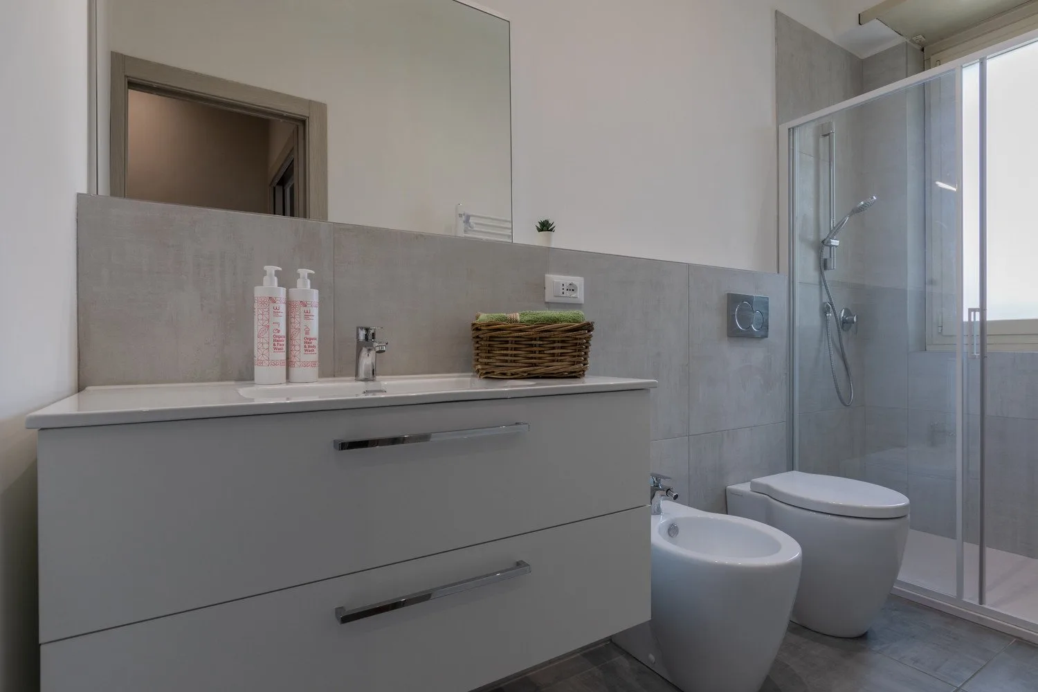 A modern bathroom with a wide vanity and glass-enclosed shower.