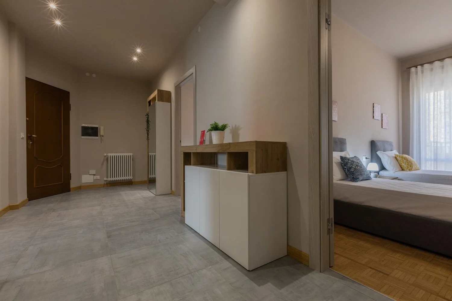 A bright hallway with a low cabinet and an open doorway to a bedroom.