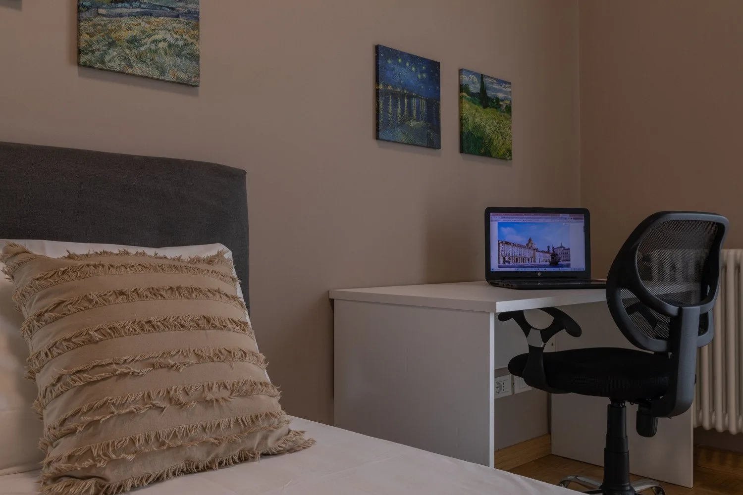A bedroom with a bed beside a desk and office chair.
