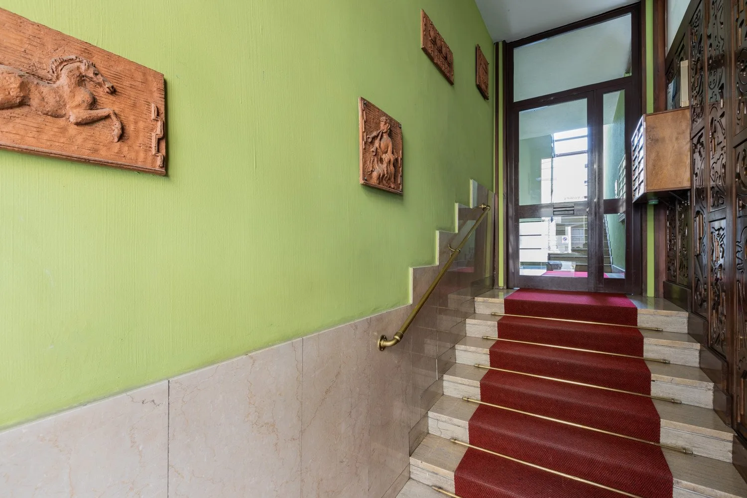 A stairway with red carpeting leads up to a glass-paneled entrance.
