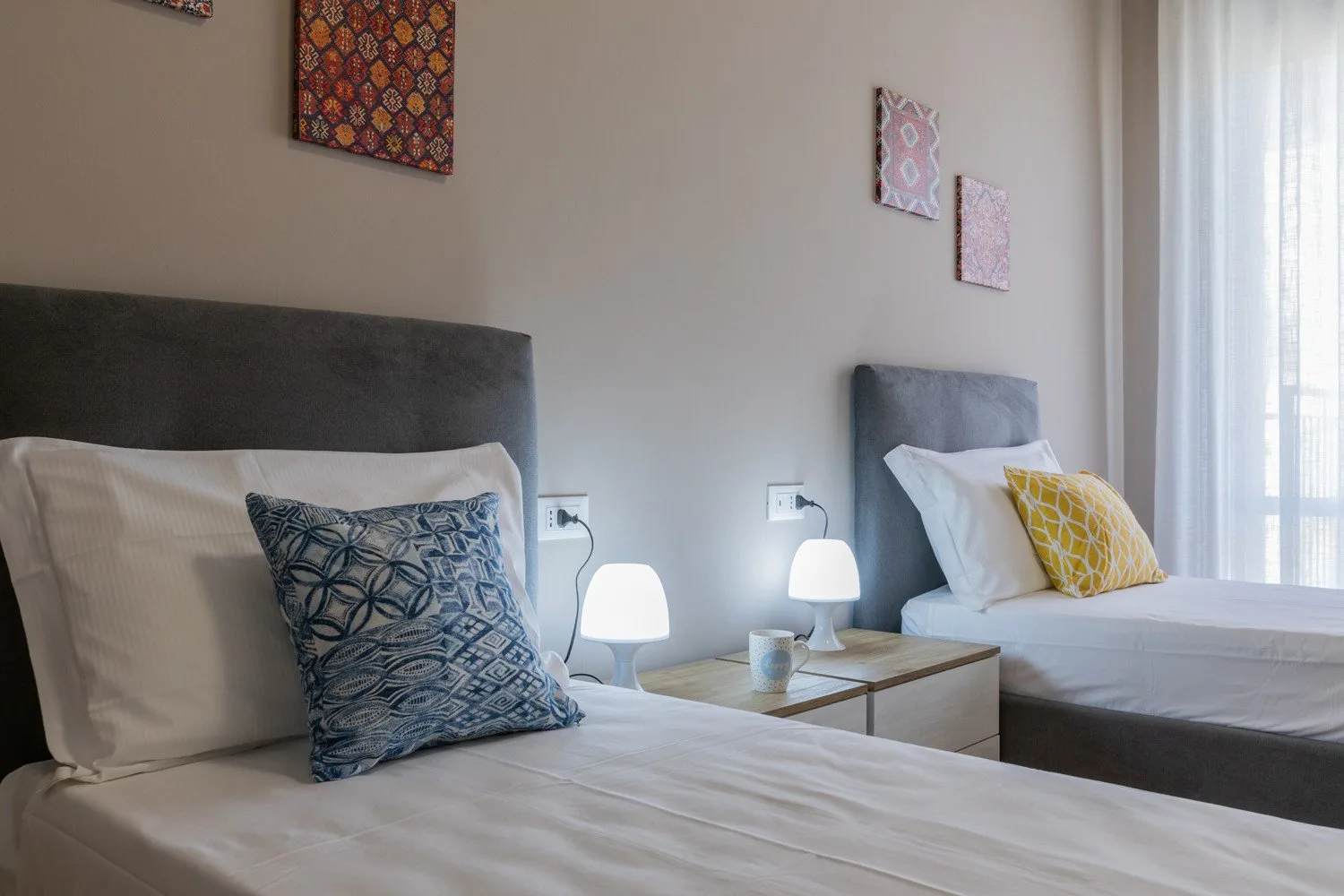 A bedroom with two beds and a shared bedside table.