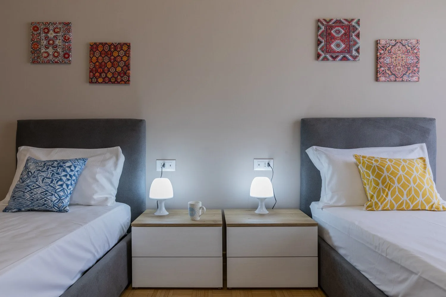 A bedroom with two beds and matching bedside tables.