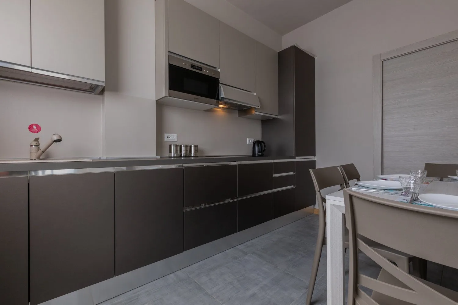 A modern kitchen with dark cabinets and a dining table.