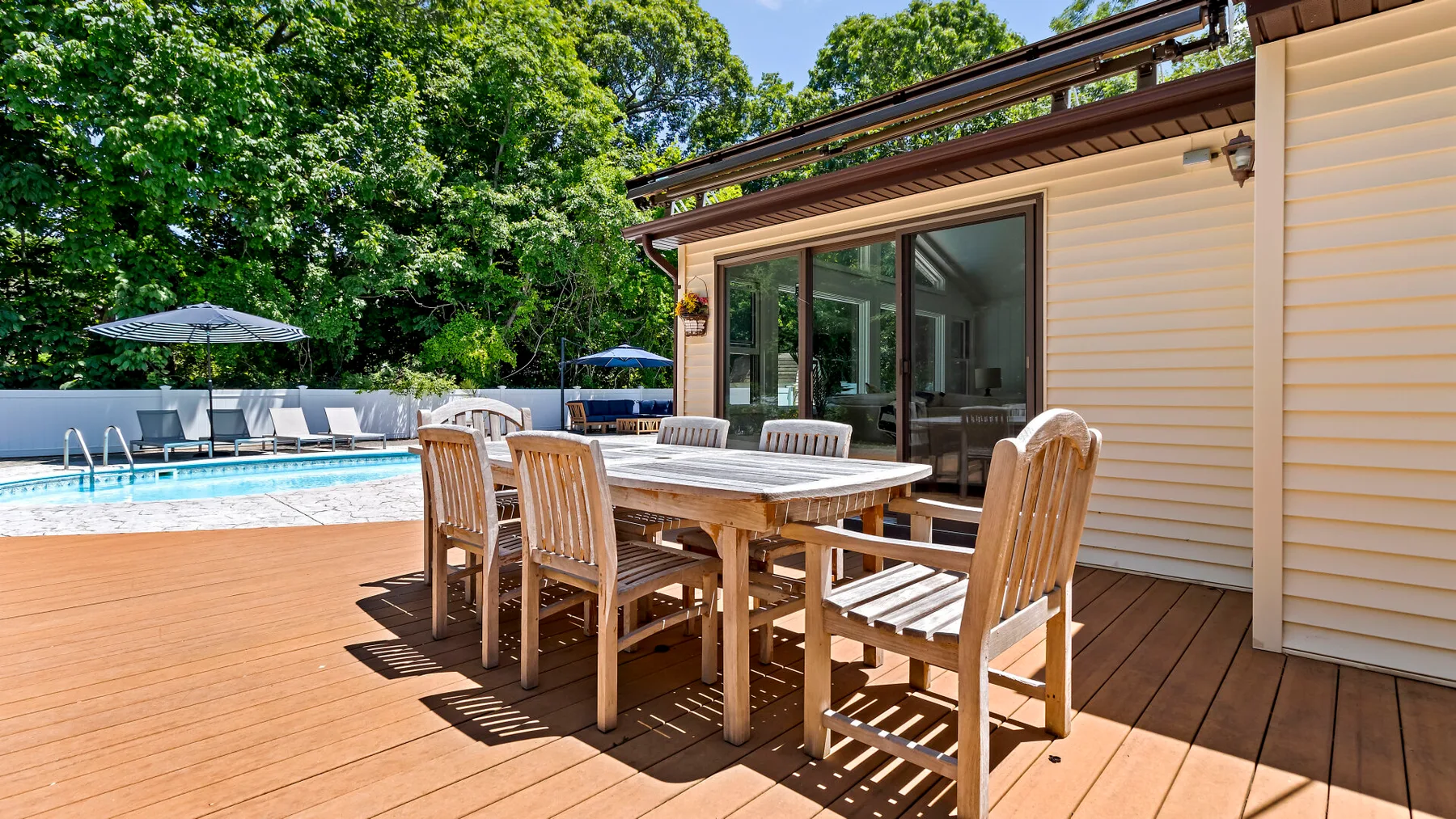 An outdoor dining area beside a swimming pool and a house.