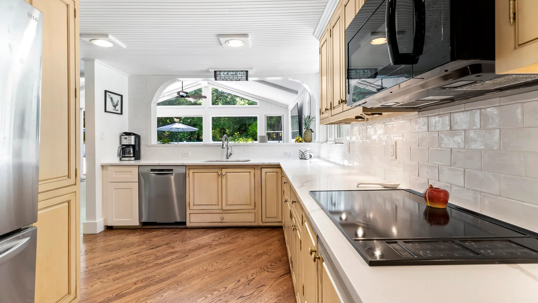 Una cocina luminosa con gabinetes de madera clara y una ventana grande sobre el fregadero.