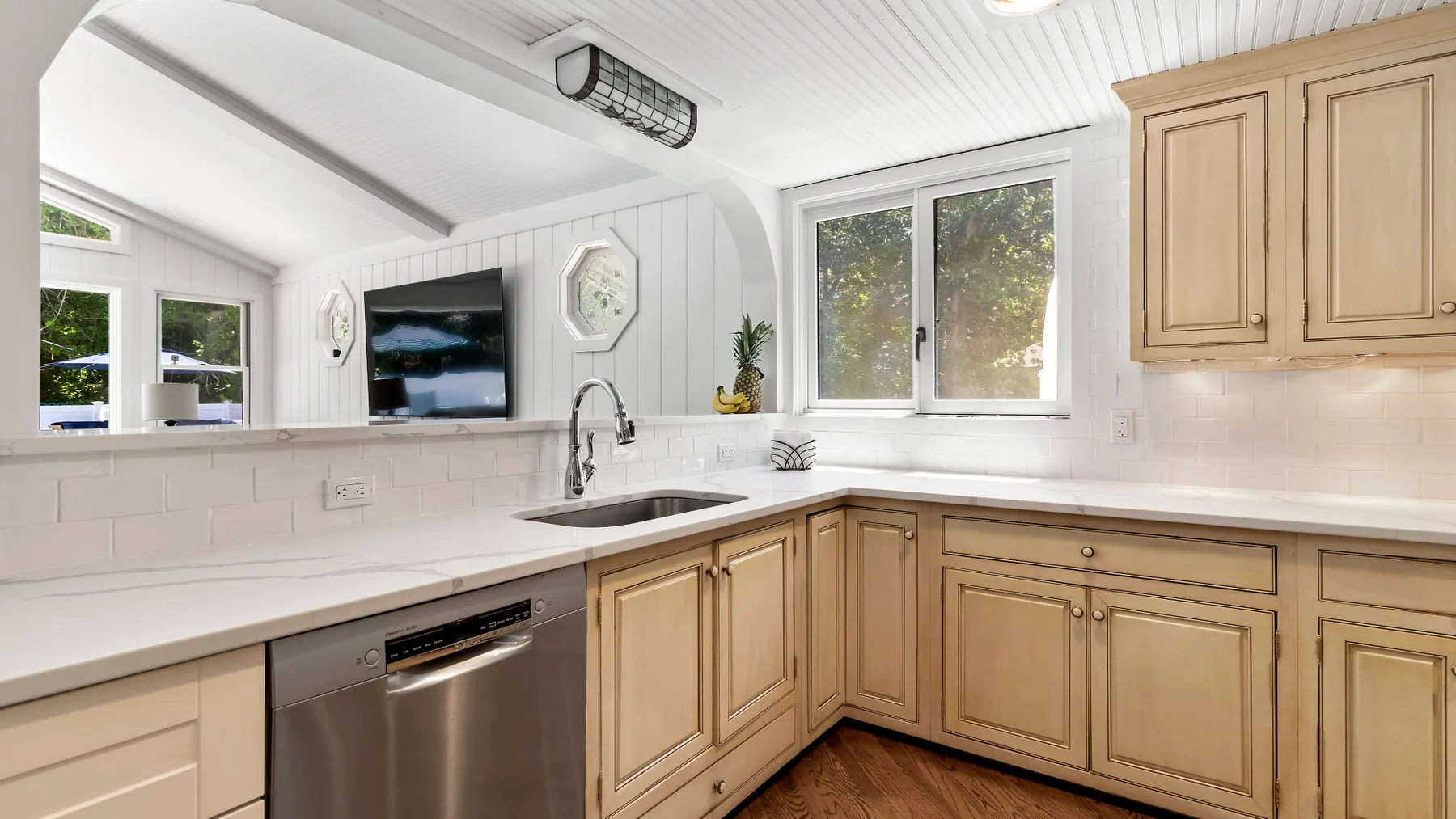 Una cocina luminosa con gabinetes de madera clara y encimeras blancas.