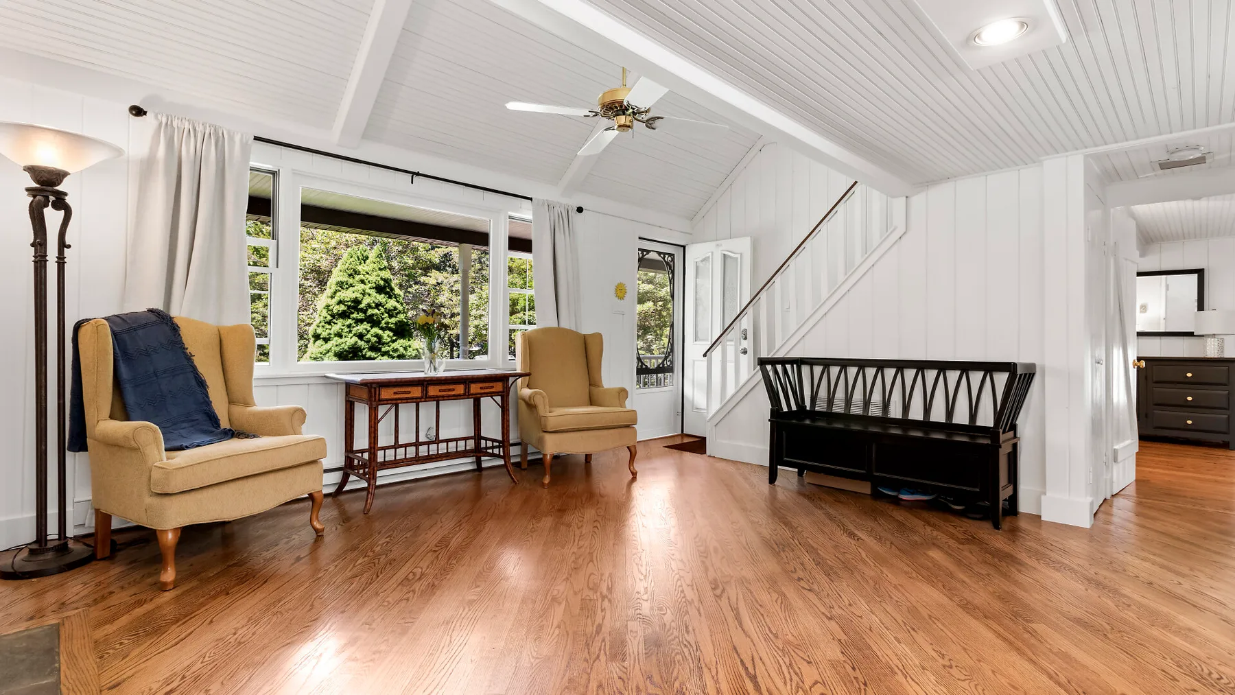 Una sala luminosa con asientos junto a grandes ventanas y una escalera.