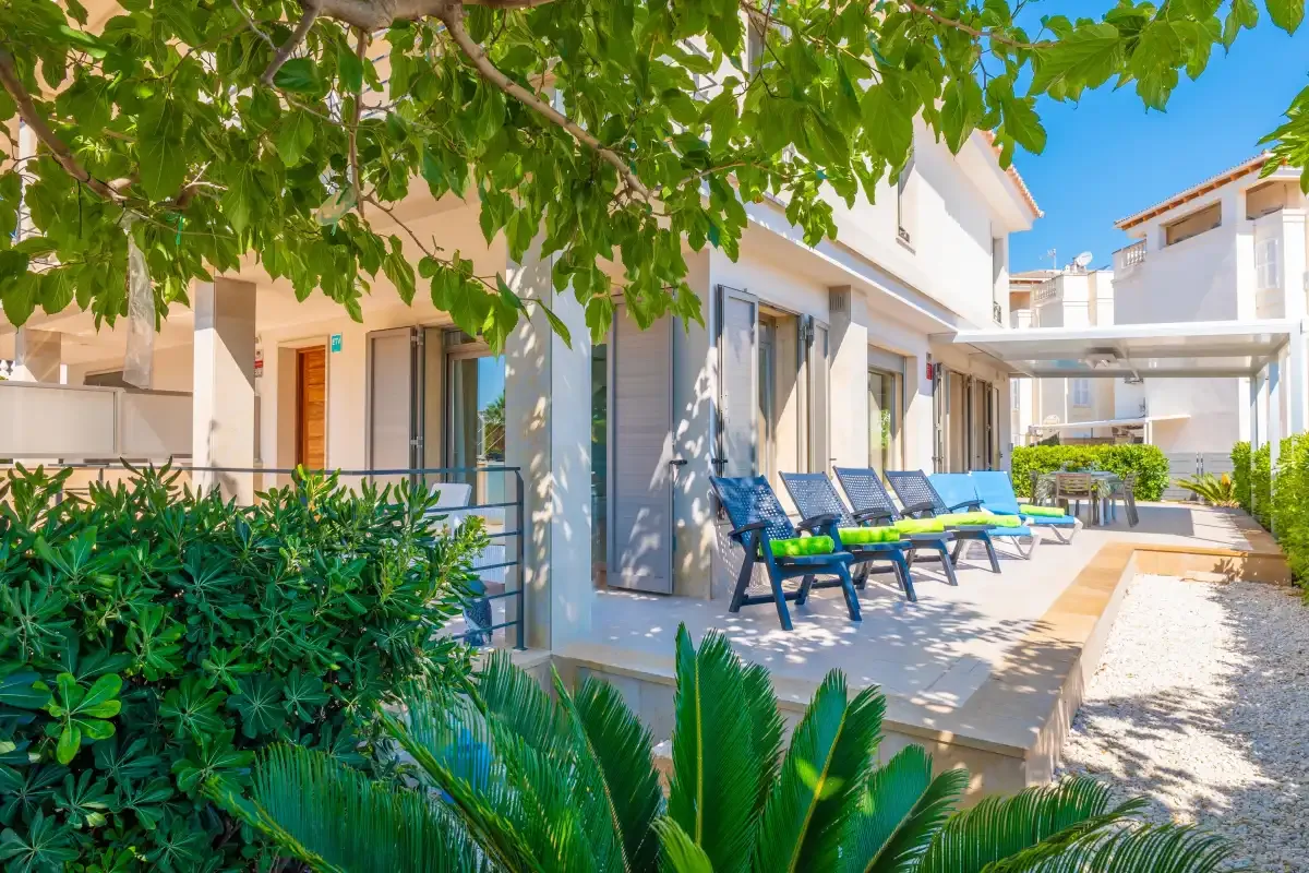 Outdoor patio with lounge seating beside a light-colored building.