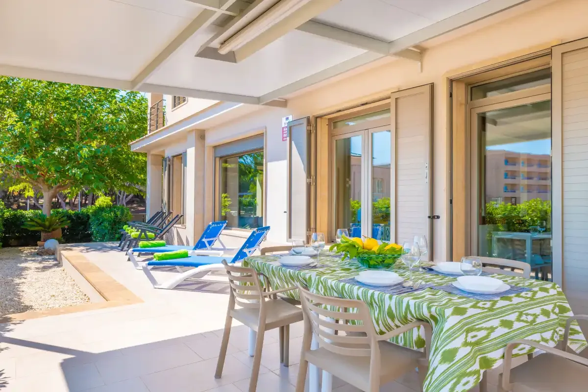 A sunny patio with a dining table and lounge chairs beside the building.