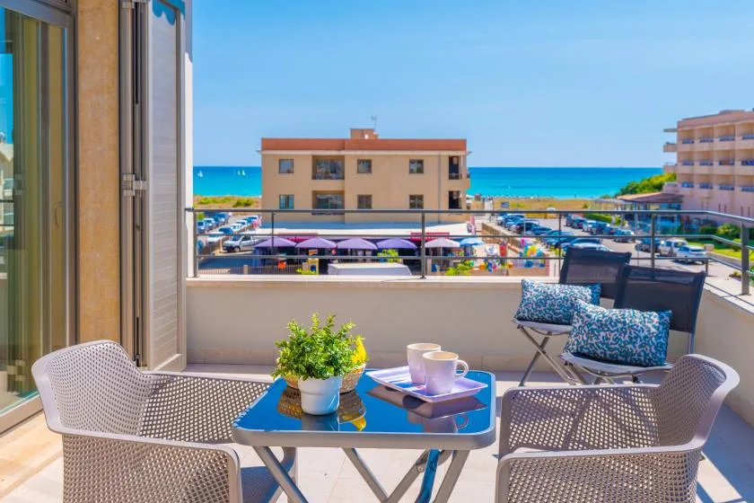 A balcony seating area overlooks the sea, with a small table and potted plant.