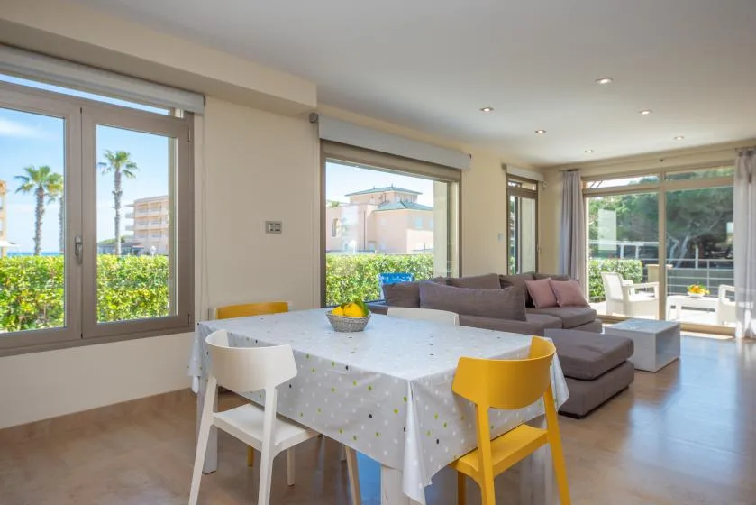 A bright dining and living area with a table beside a sofa and large windows.