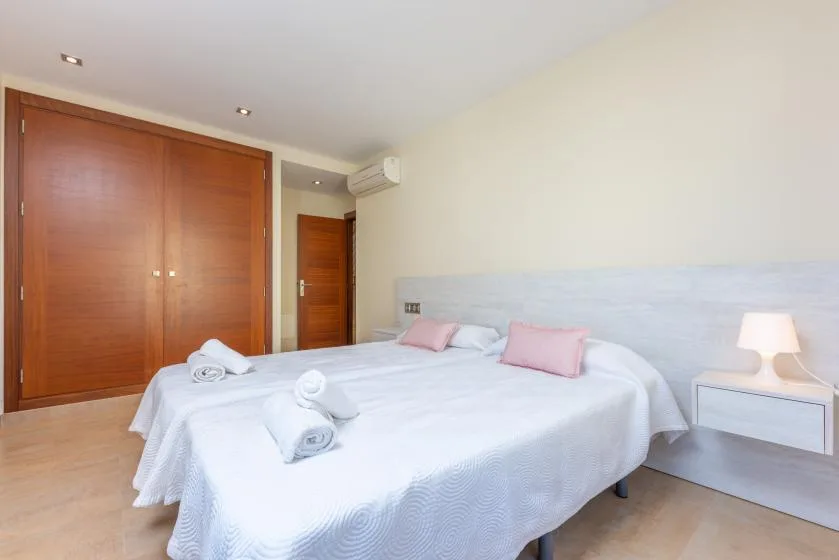 A bedroom with a large bed, folded towels, and wooden wardrobes.