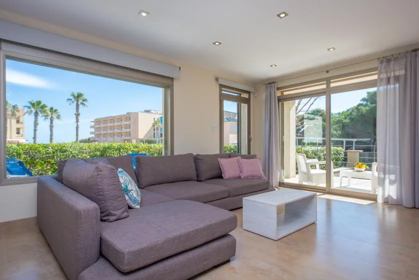 A bright living room with a sectional sofa beside large windows opening onto a terrace.