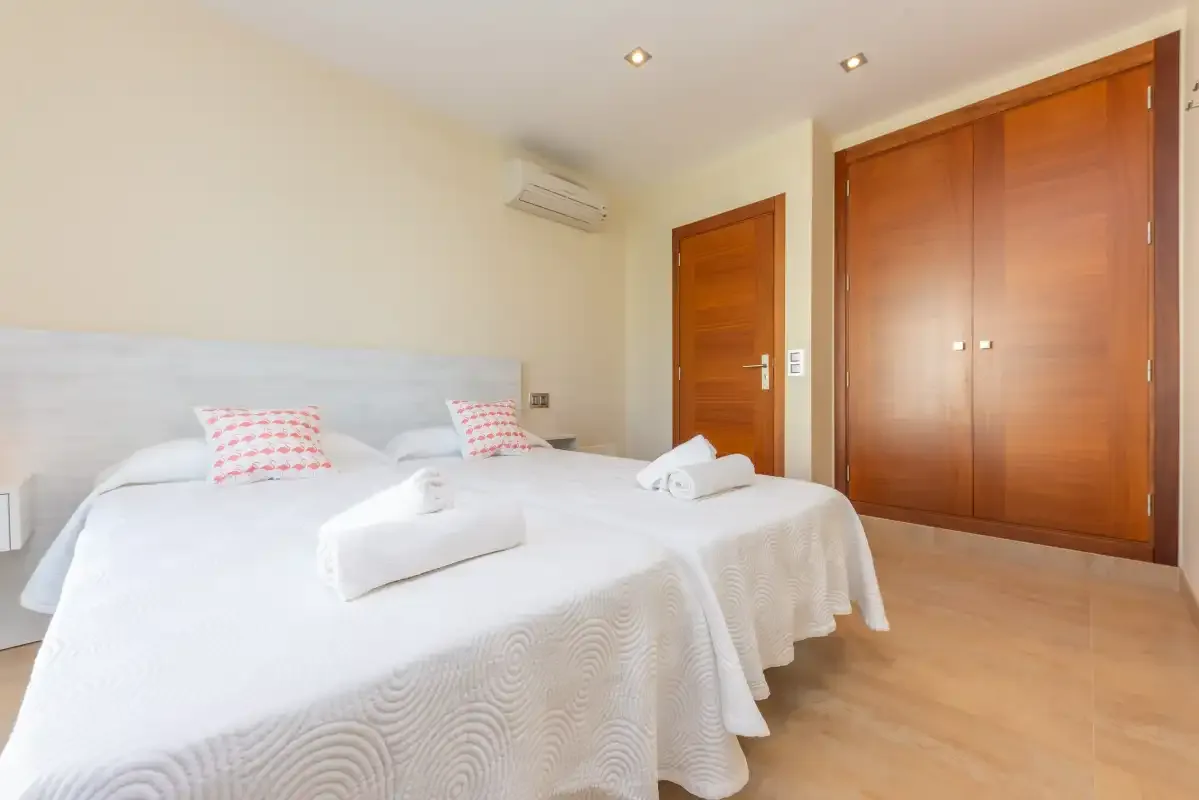 A bright bedroom with white bedding and wooden doors.