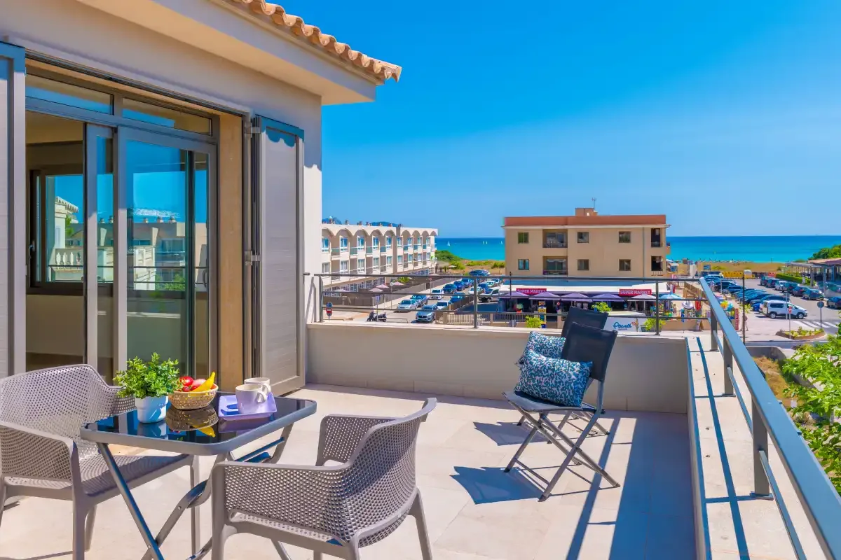 A sunny terrace overlooks nearby buildings and the sea.