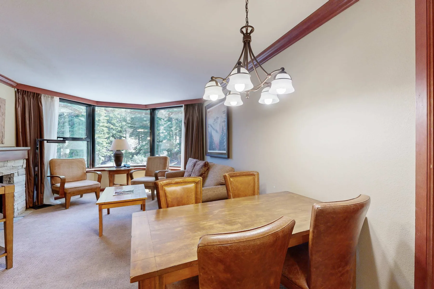 Un comedor y zona de estar con una mesa de madera y grandes ventanas.