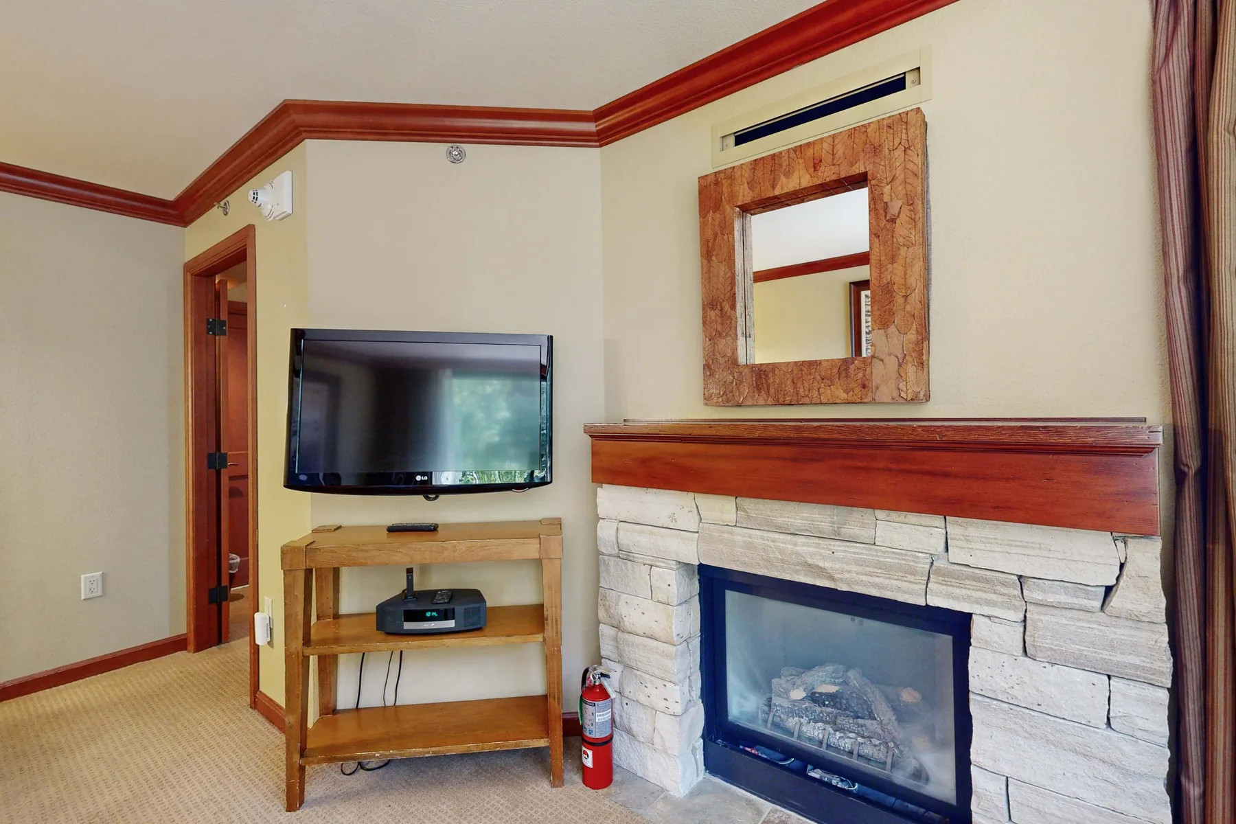 Una sala de estar con un televisor junto a una chimenea y un espejo de pared.