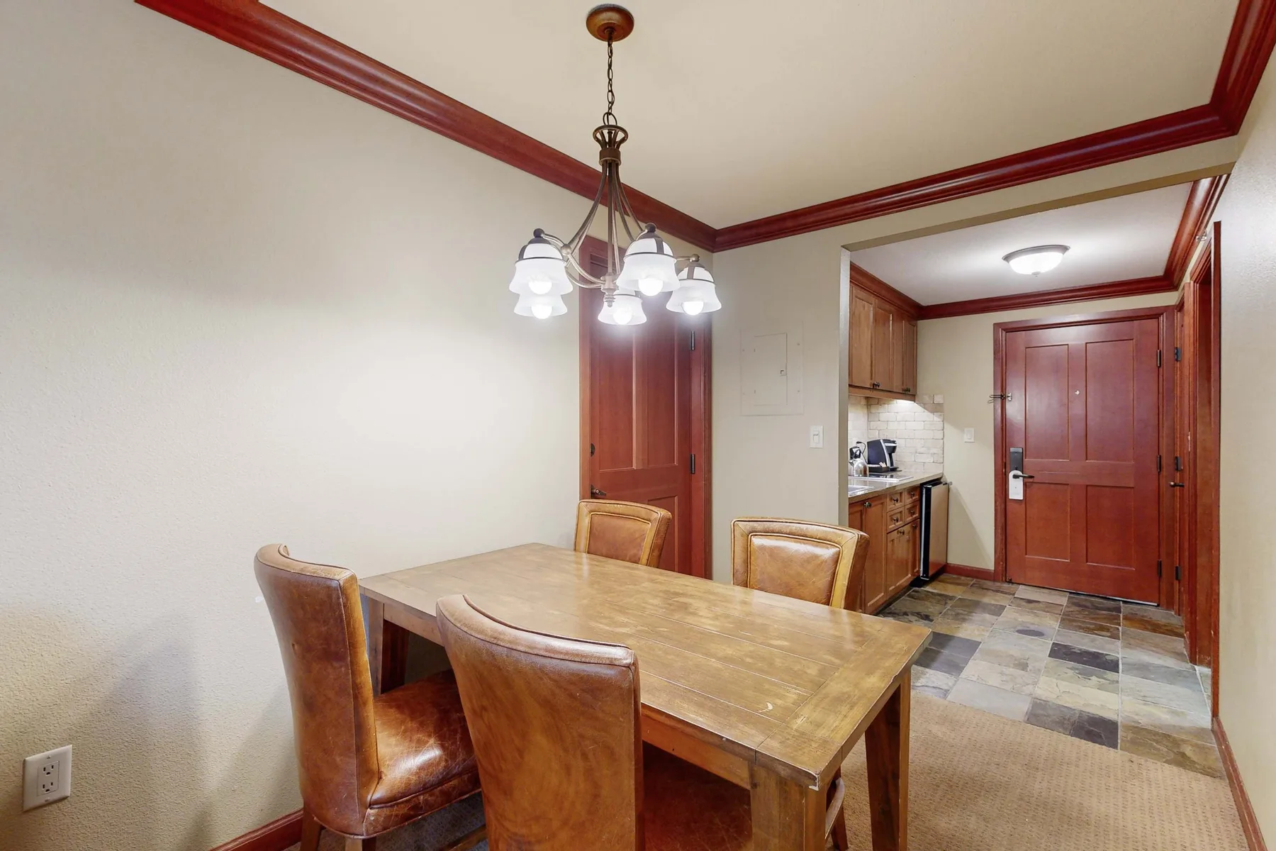 Un comedor con una mesa de madera y una pequeña cocina al fondo.