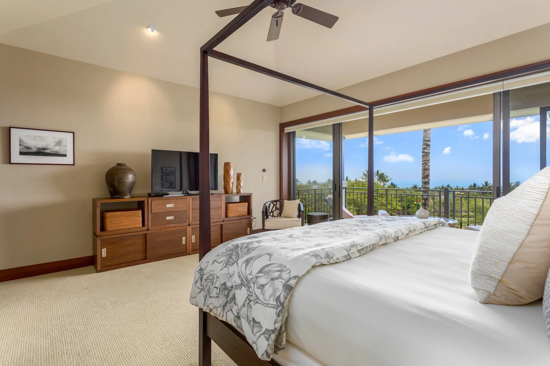 Un dormitorio con cama con dosel y grandes ventanas con vistas al balcón y al mar.