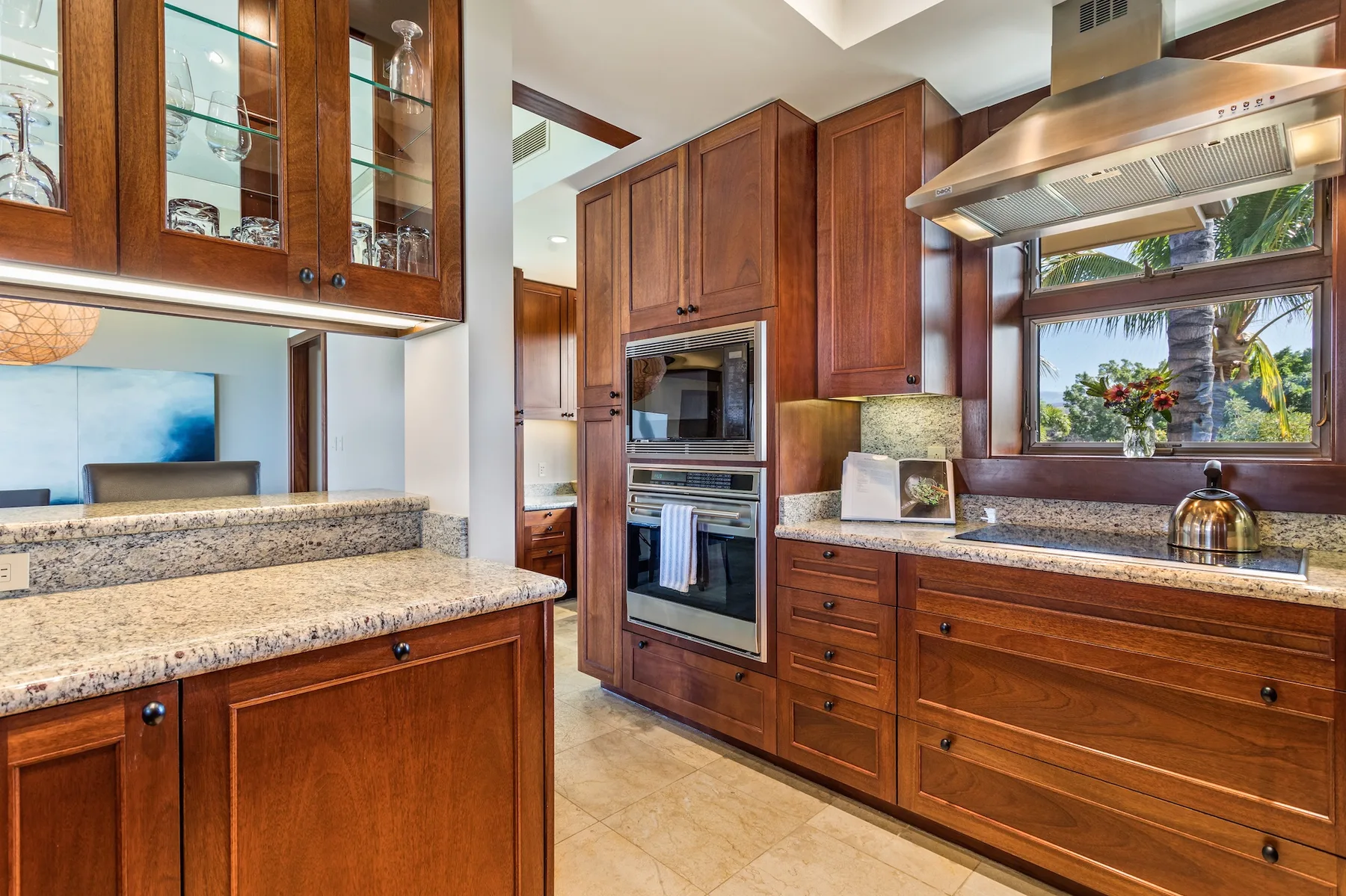 Una cocina con gabinetes de madera, encimeras de piedra y hornos empotrados.