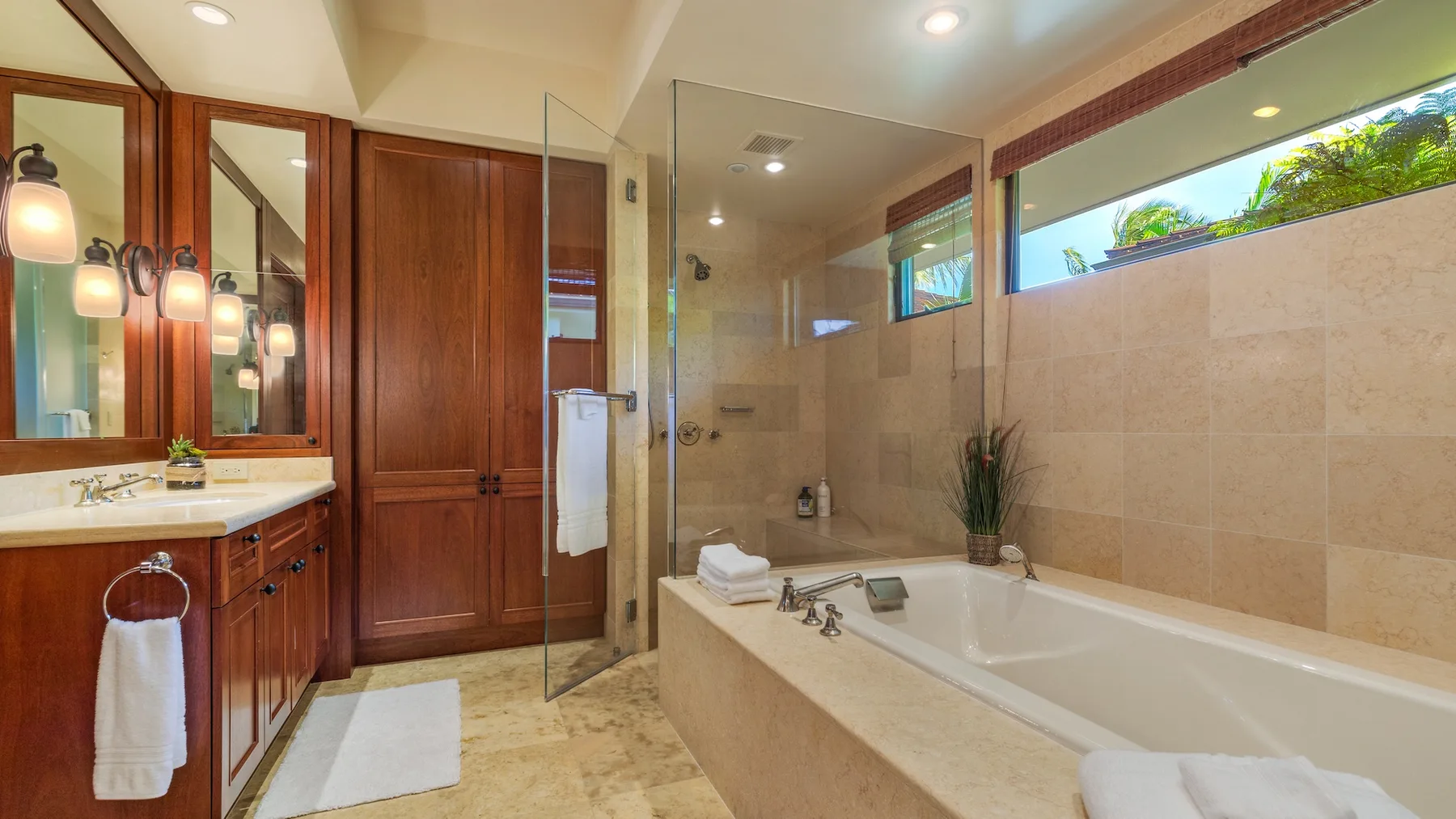 Un baño con bañera, ducha de vidrio y tocador de madera.