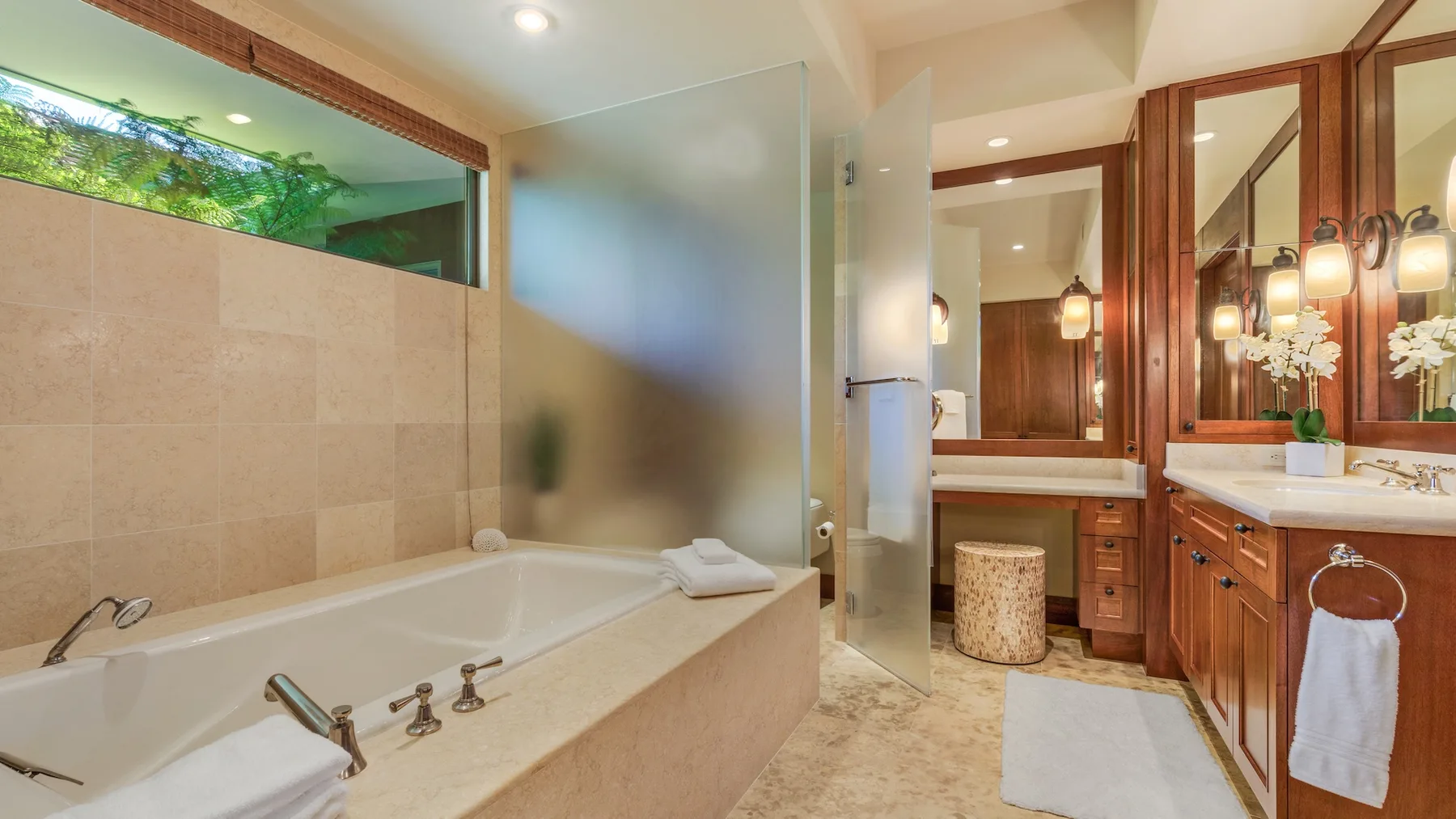 Un baño con bañera, panel de ducha de vidrio y tocador de madera.