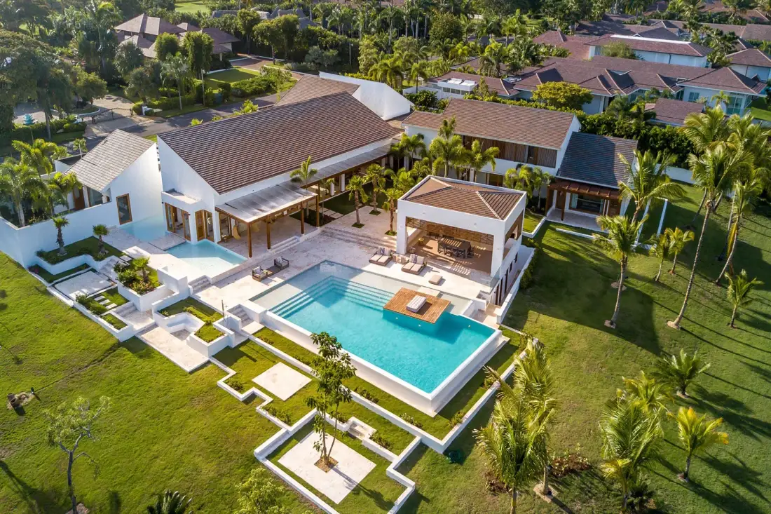 Vista aérea de una villa moderna con una gran piscina y jardines.
