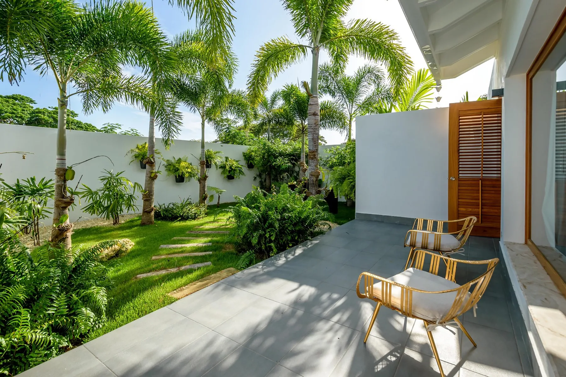 Un patio con asientos al aire libre junto a un frondoso jardín tropical.