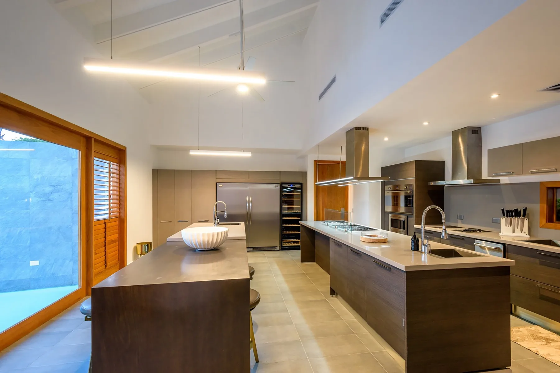 Una cocina moderna y espaciosa con una gran isla y puertas de vidrio.