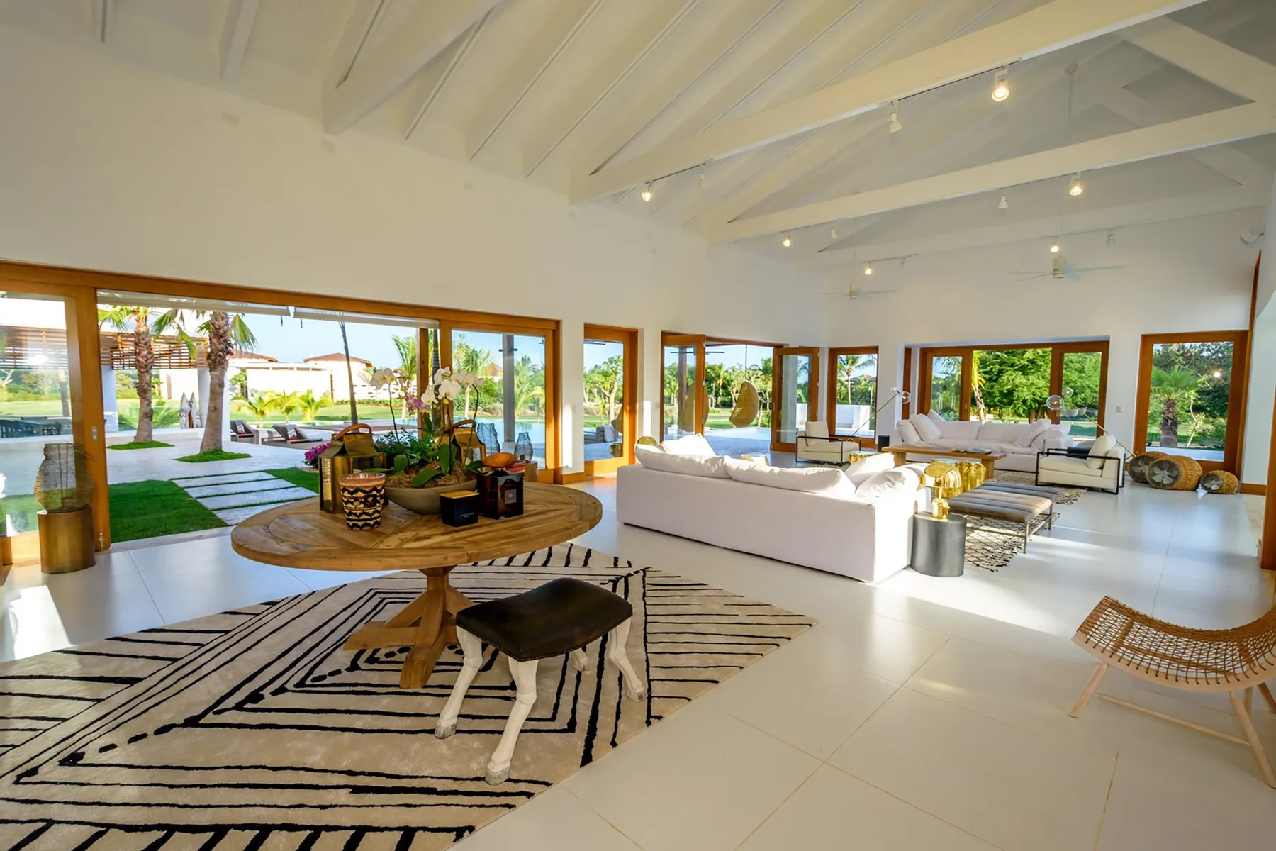 A bright open living room with seating and large windows overlooking a garden.