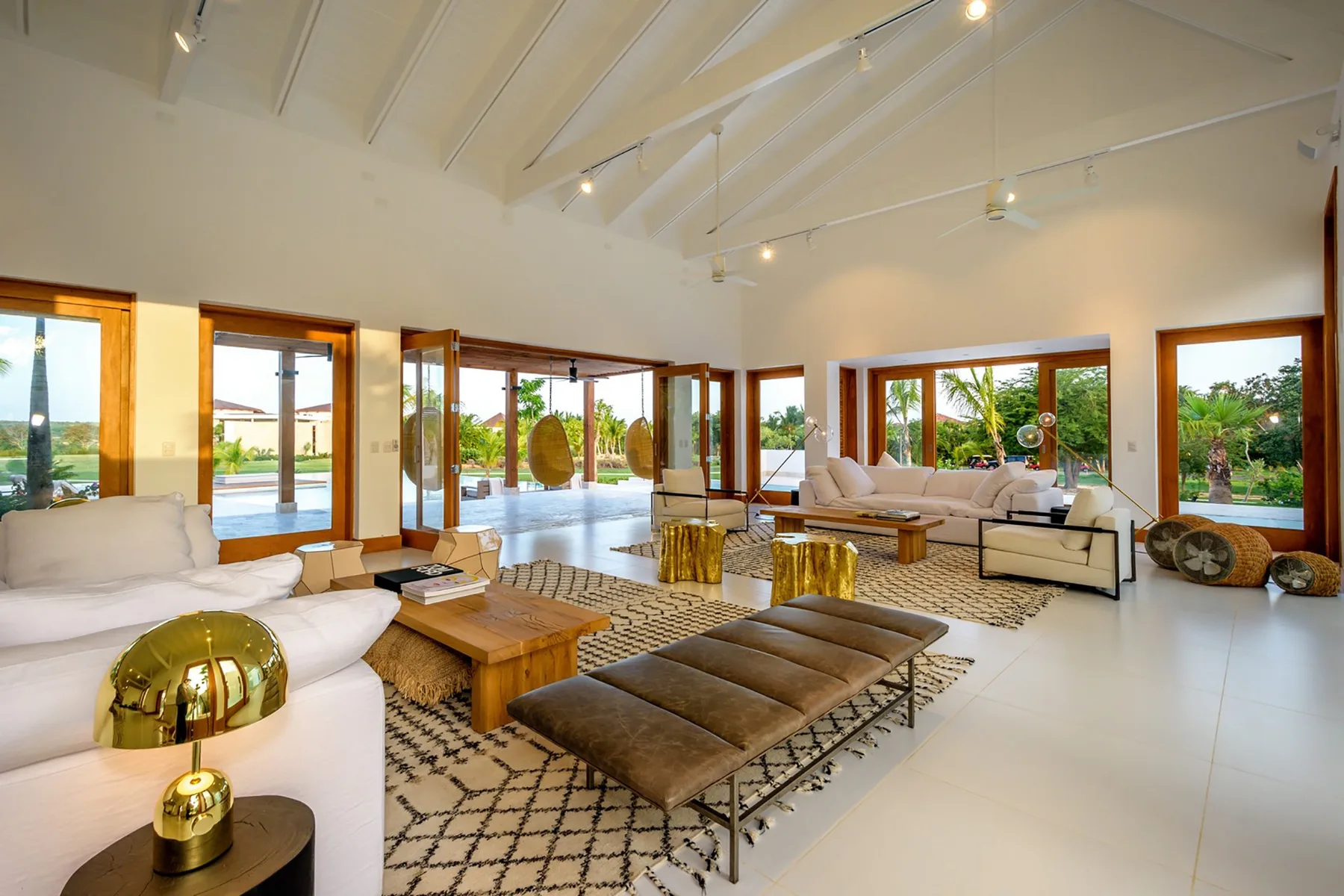 A spacious living room with seating around a low table and large windows.