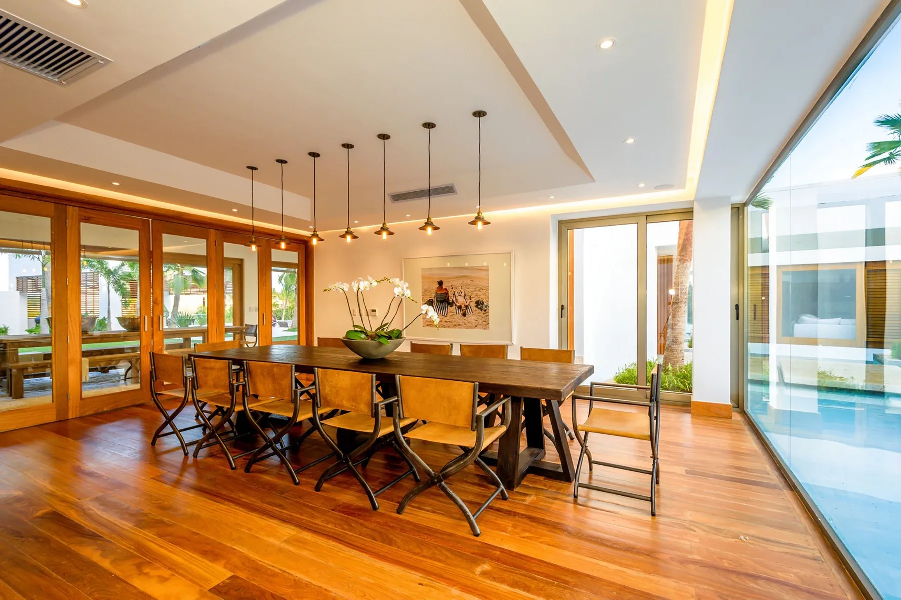 Comedor con una mesa larga de madera junto a grandes puertas de vidrio.