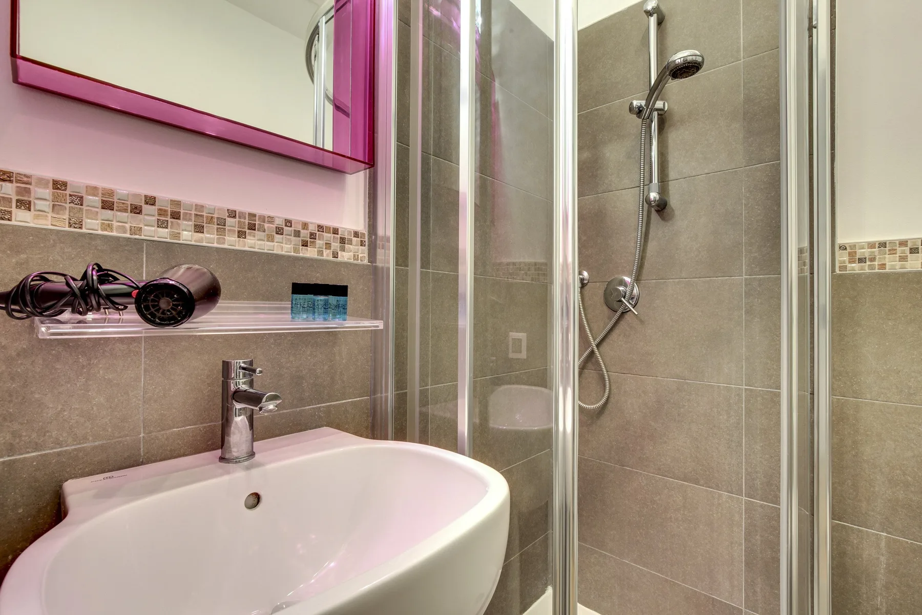 Un baño con un lavabo junto a una ducha de vidrio.